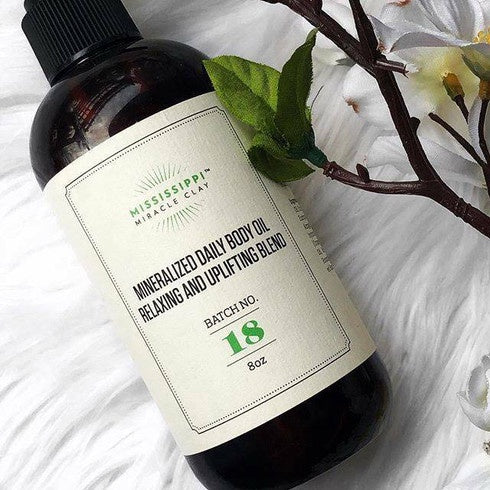 Mineralized Daily Body Oil bottle on white with flowers, a lightweight daily body oil