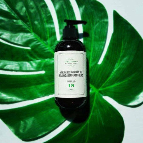 Mineralized Daily Body Oil bottle against a green leaf