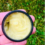 Open Overnight Reparative Facial Balm showing the rich balm, held in hand