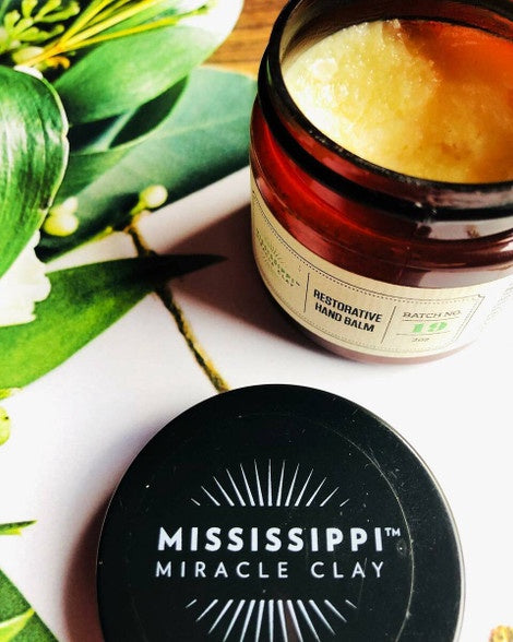 Restorative Hand Balm jar styled with tropical leaves