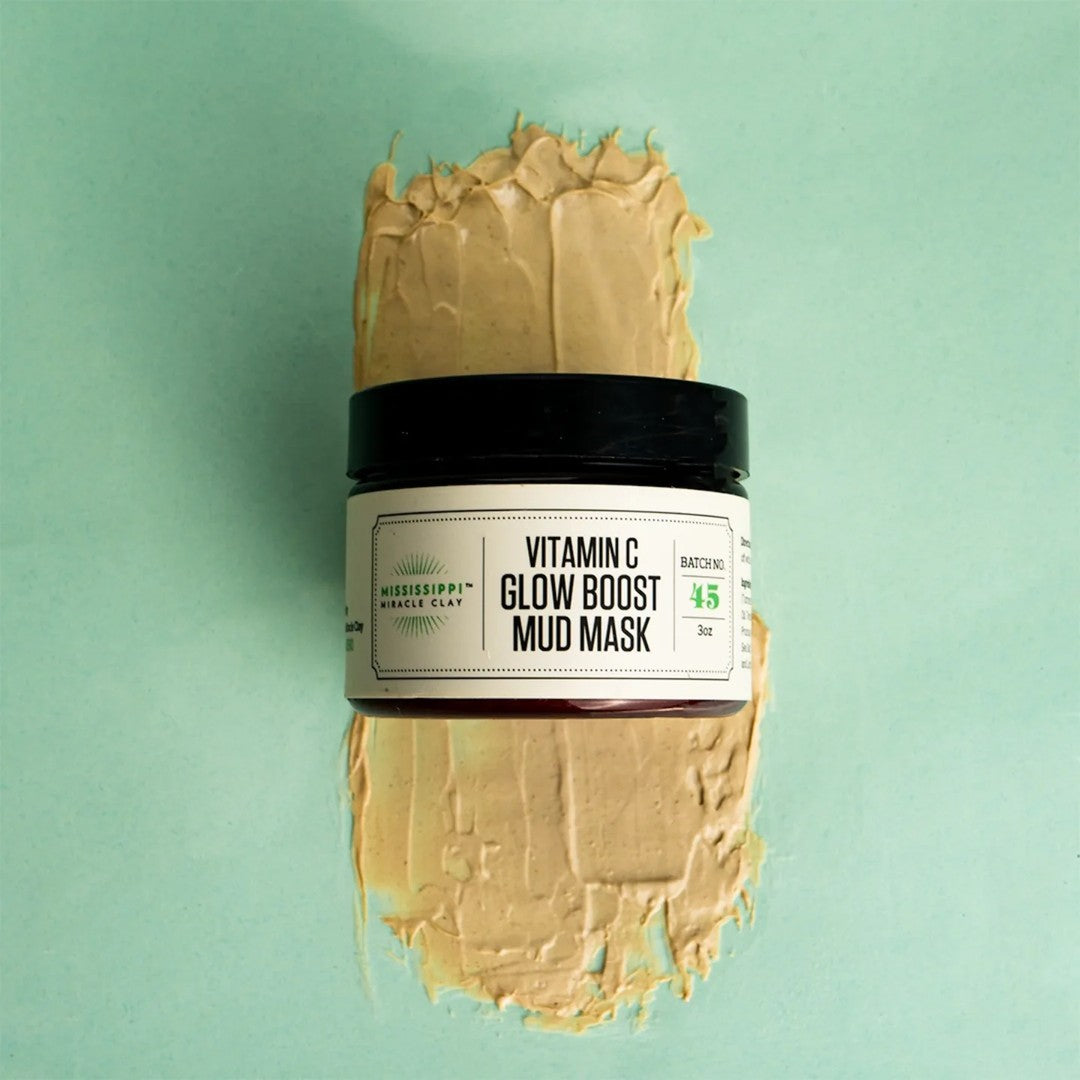 Vitamin C Glow Boost Mud Mask jar on a swatch of the golden mask